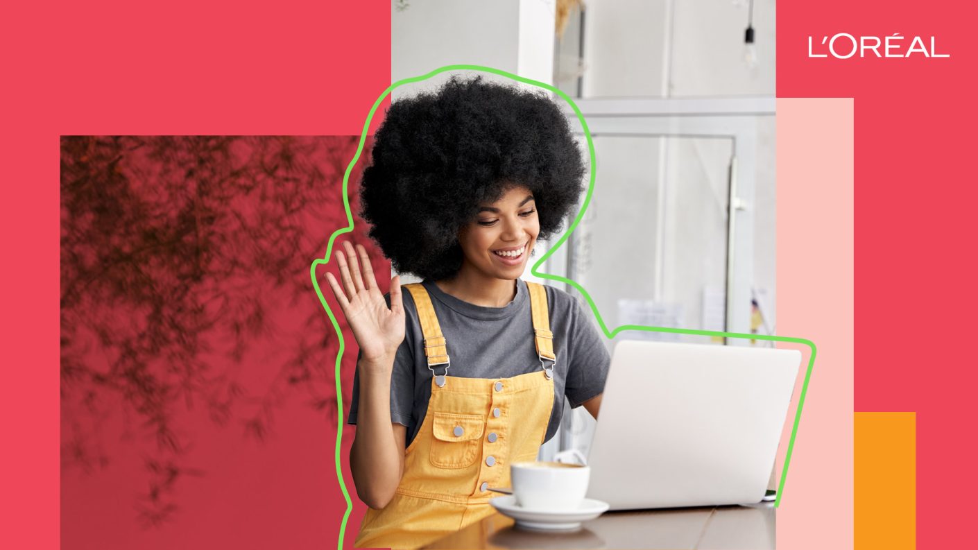 Woman waving and smiling at her laptop screen