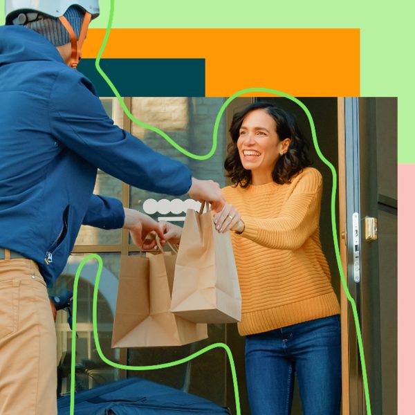 Delivery person handing over brown bags to another person at the door