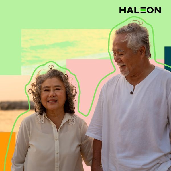 Elderly couple holding hands walking along the beach