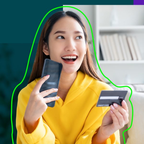 Smiling Asian woman, holding a bank card and a smartphone