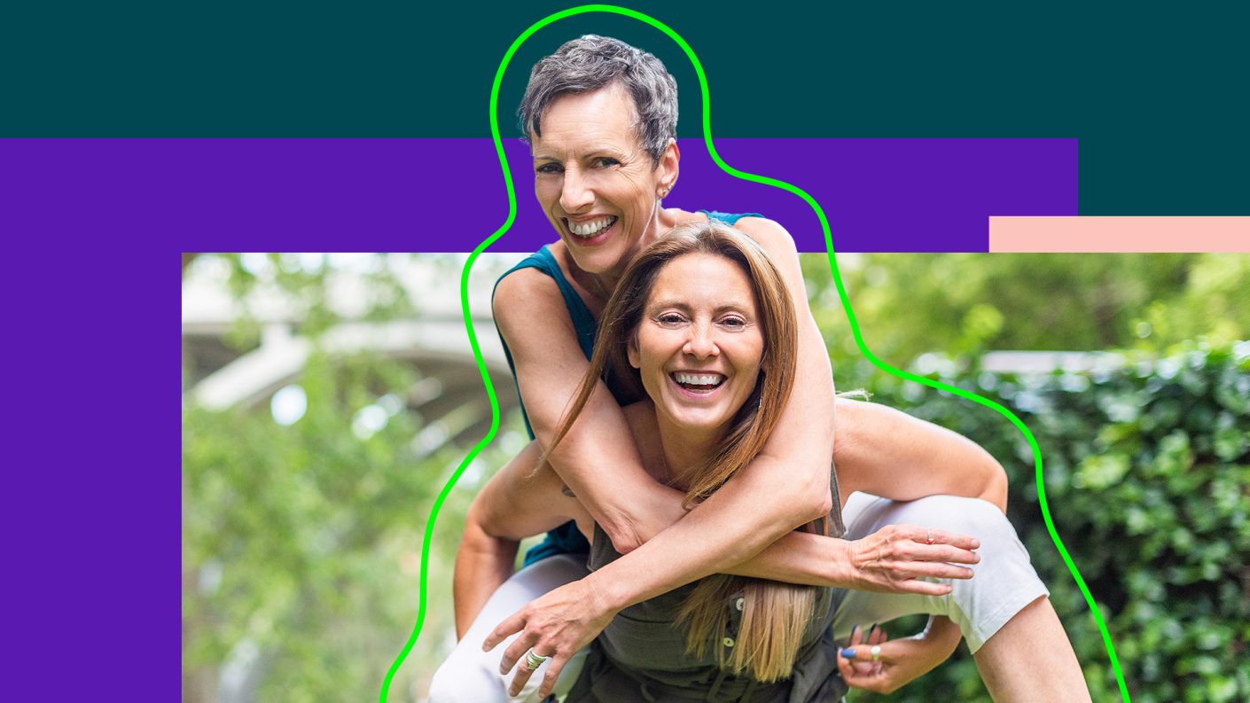 Two women having fun, one sits on the back of the other one.